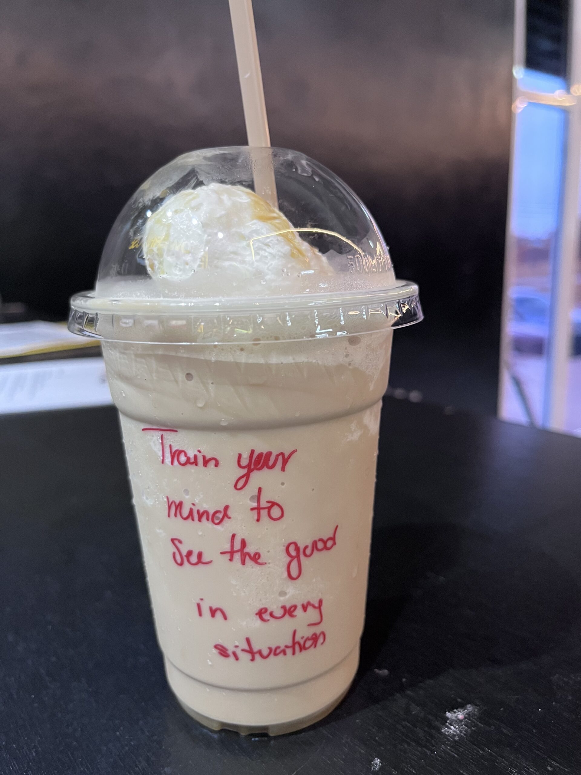 This photo shows a frozen coffee with a train your mind quote written on the take away cup.